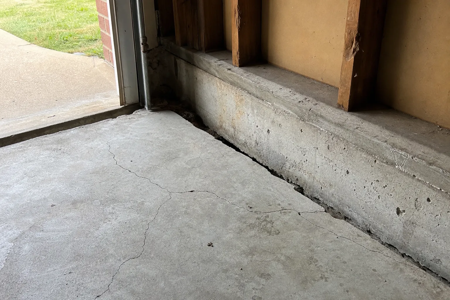 Sunken garage floor with settlement cracks along the slab joint in a Tulsa Oklahoma home