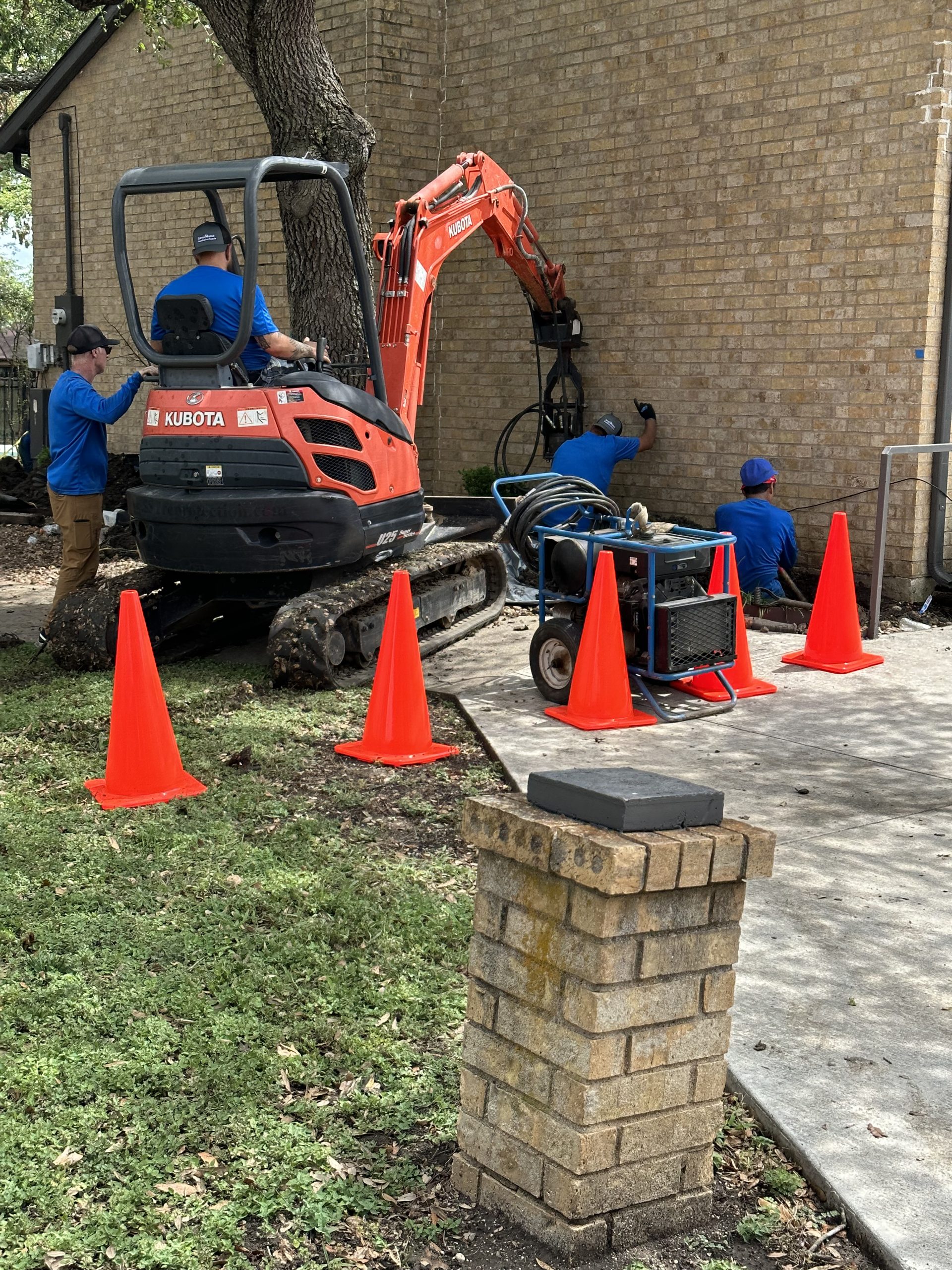 Level Home crew installing helical piers with a Kubota mini excavator at a Tulsa residential foundation repair job