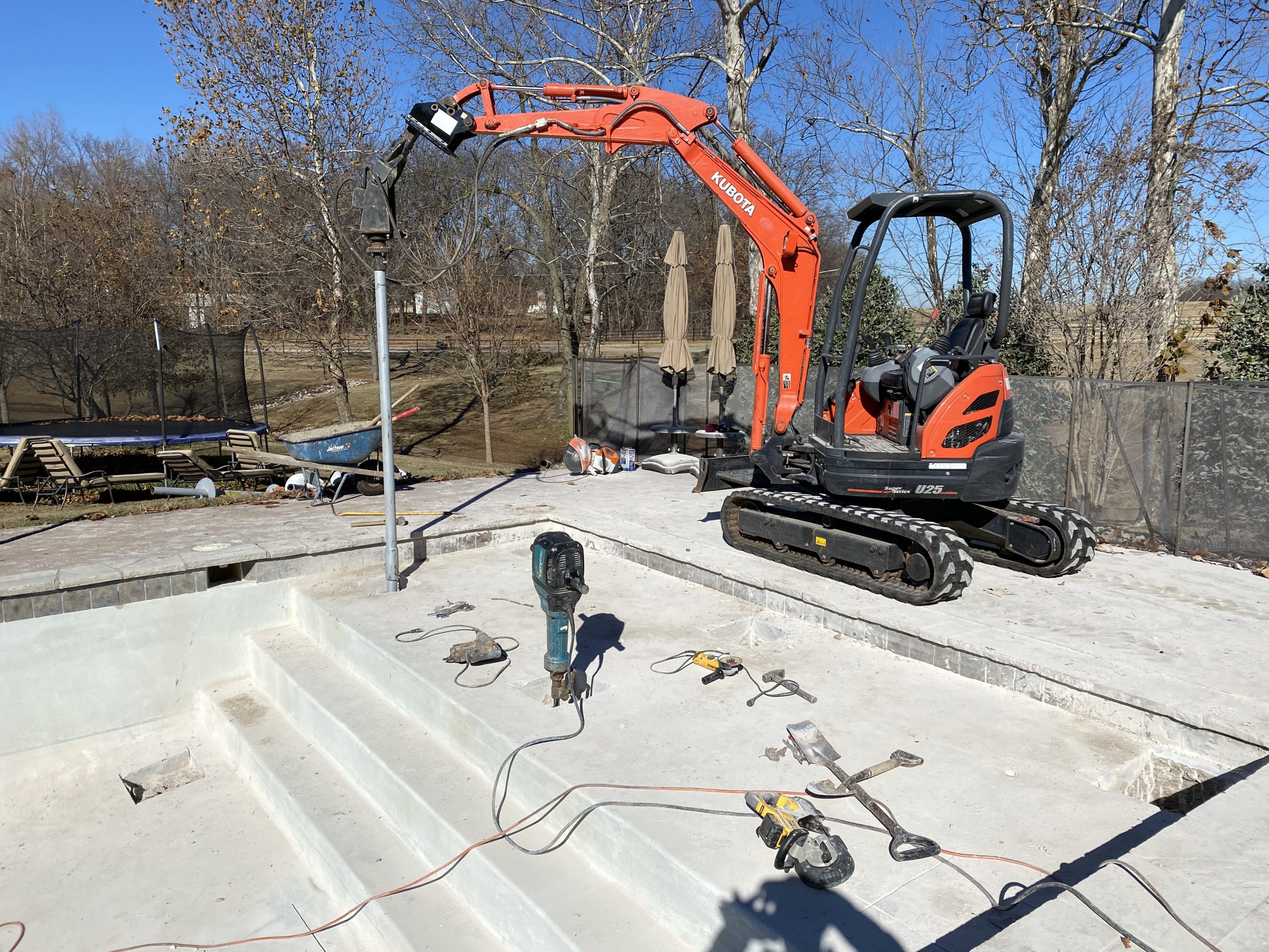 Kubota U25 mini excavator driving a helical pier into concrete during foundation stabilization in Tulsa