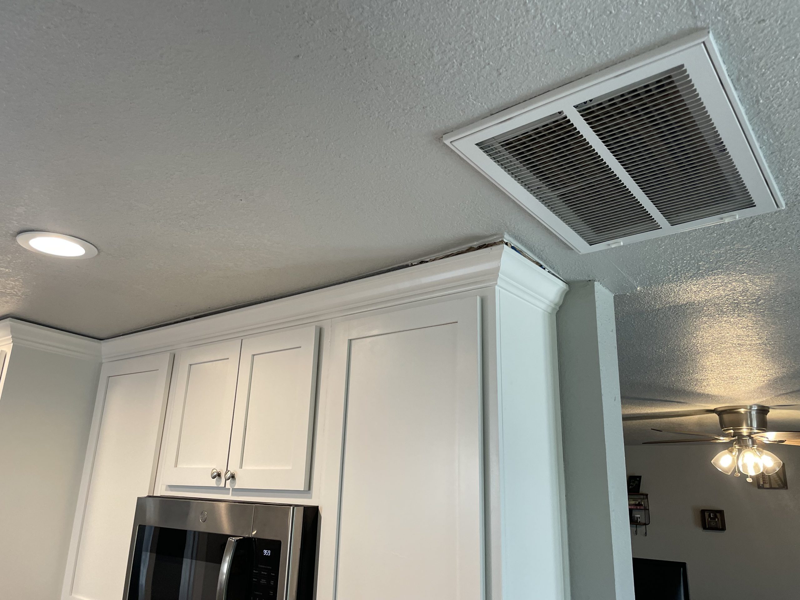 Gap between white kitchen cabinets and ceiling caused by slab foundation settlement in a Tulsa home