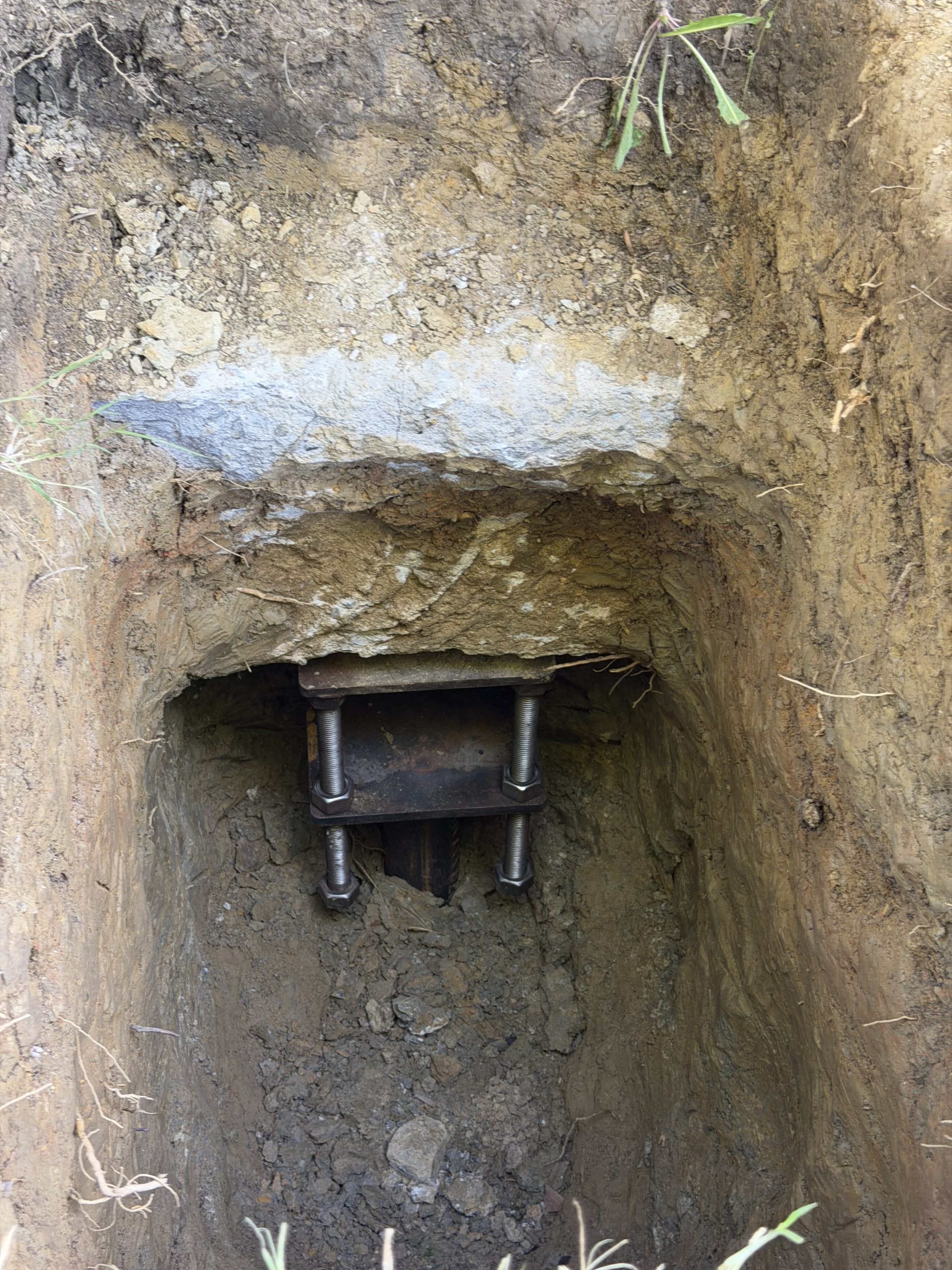 Steel pier foundation bracket bolted to concrete footing during installation in Tulsa Oklahoma