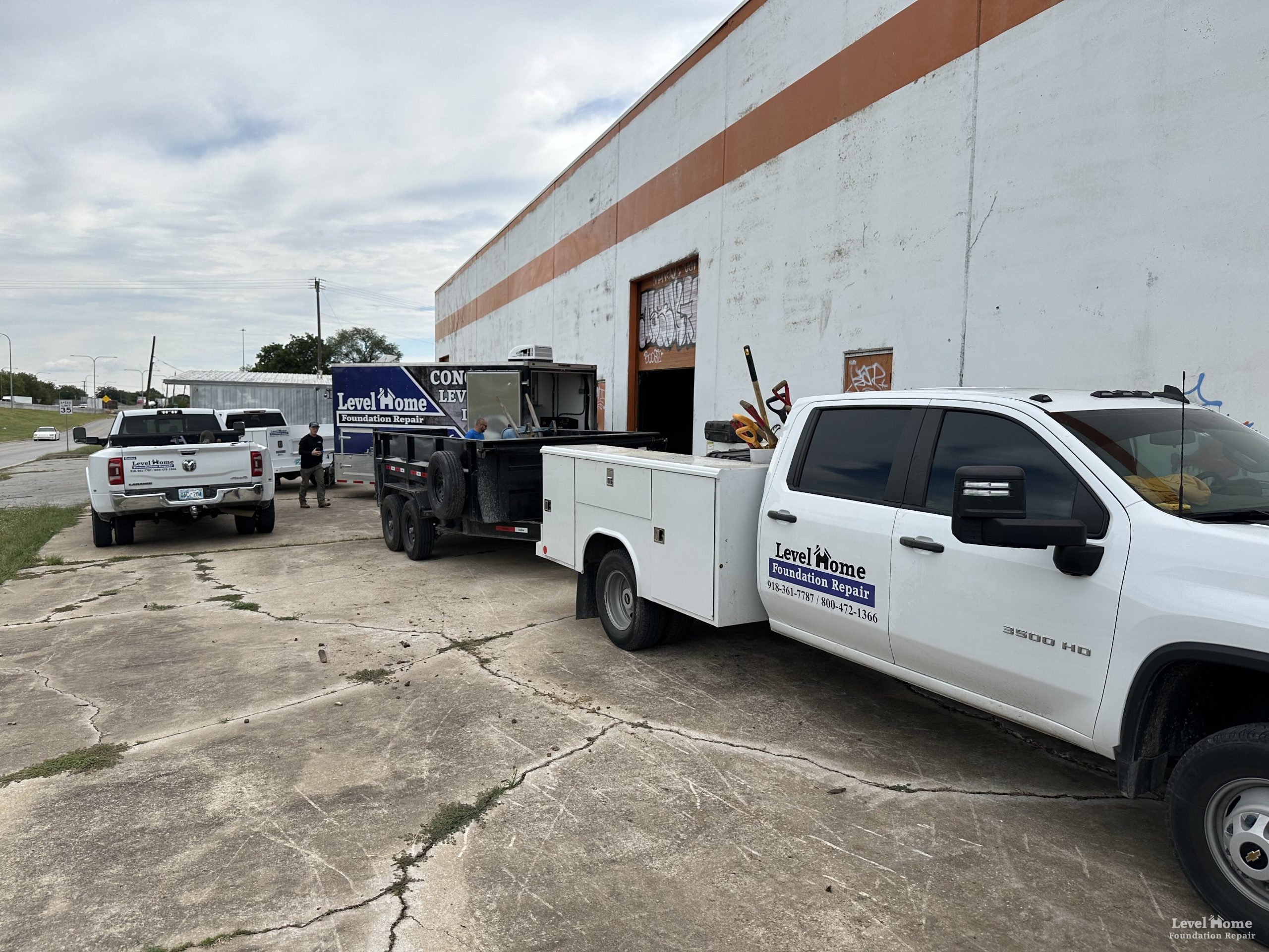 Level Home Foundation Repair fleet vehicles staged at an industrial commercial job site