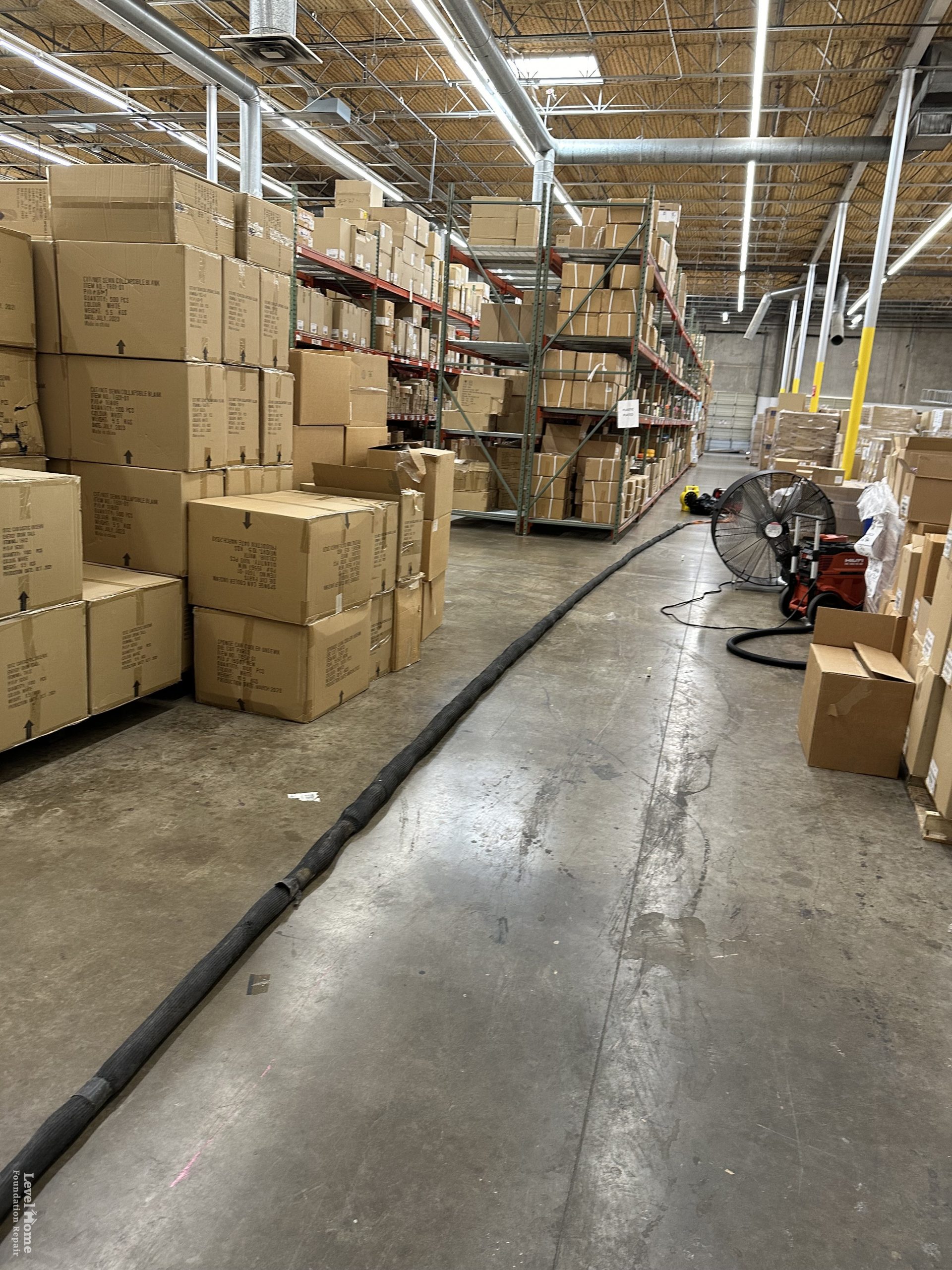 Warehouse interior with storage shelving showing floor settlement along the concrete slab