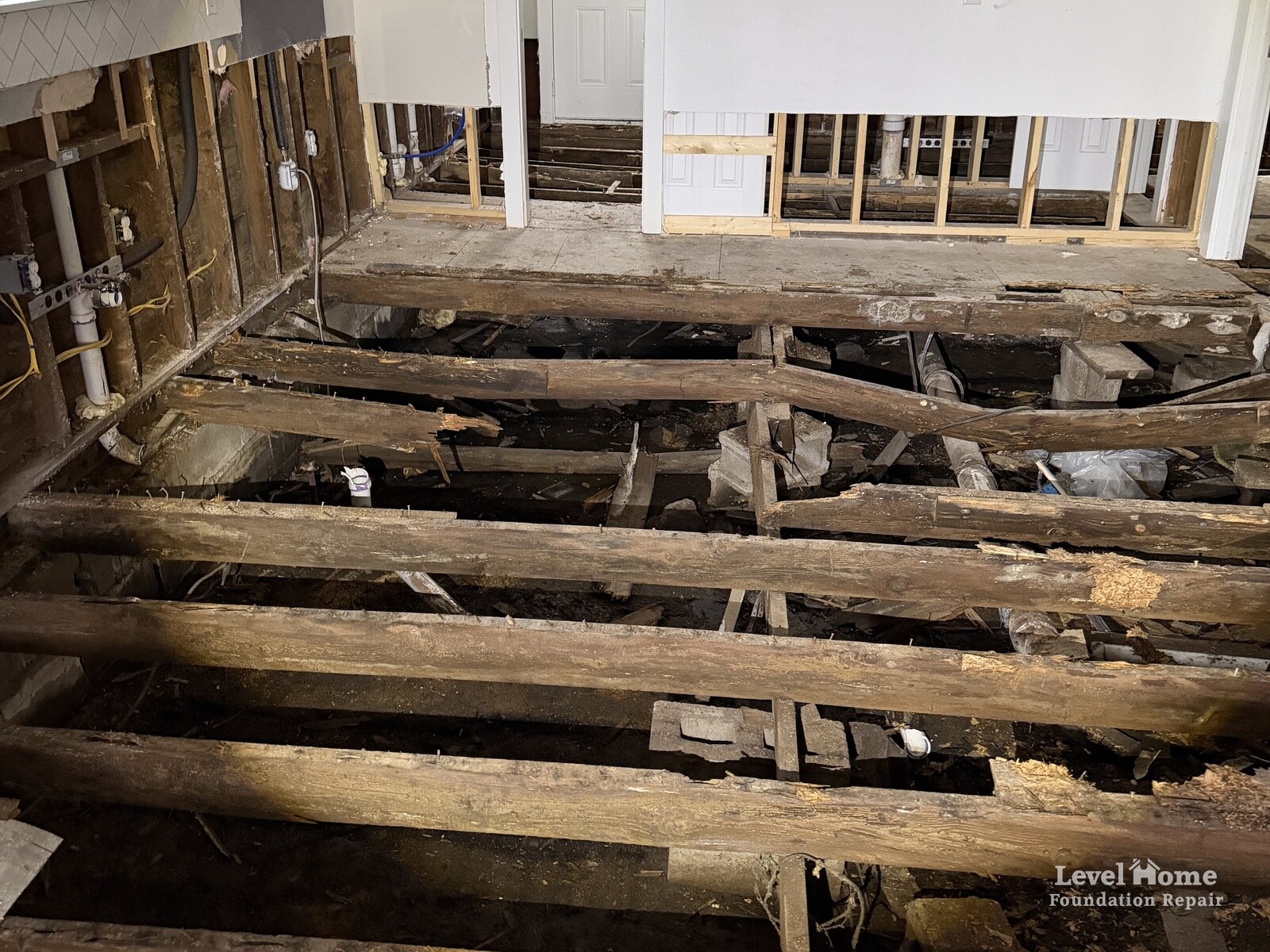 Rotted floor joists exposed above a crawl space after the subfloor was removed inside a home