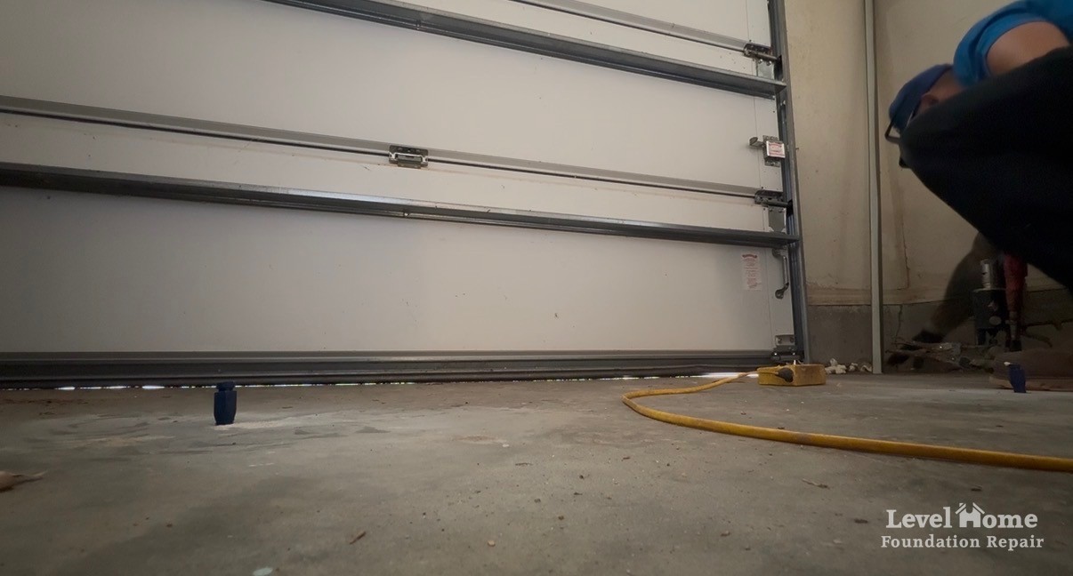 After photo from the same spot showing the garage door seal resting on the lifted slab with the daylight gap closed and a Level Home crew member nearby